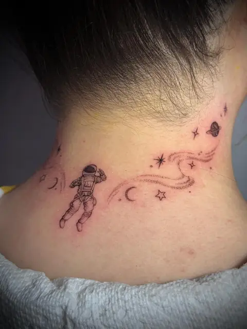 An astronaut at the nape, with stars, moons, and a planet around him.