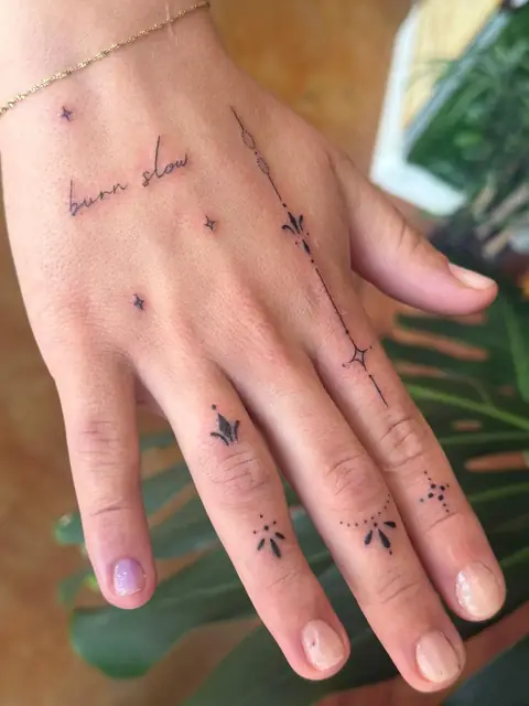 “burn slow” on the back of the hand, with stars and ornamental marks on the fingers.