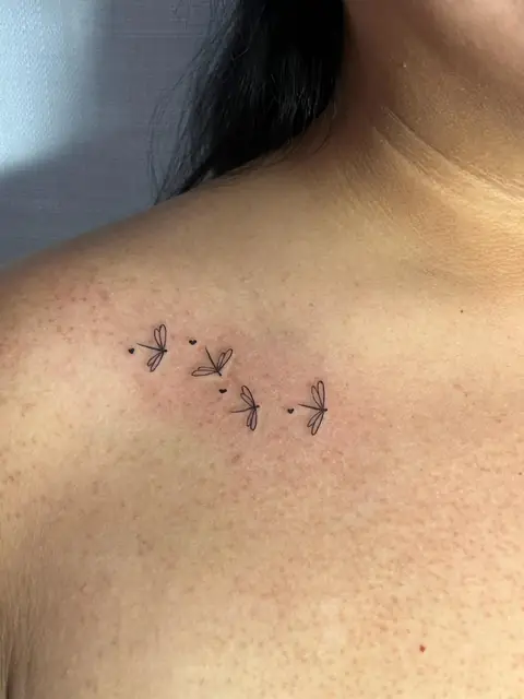 Four tiny dragonflies and hearts across the collarbone.
