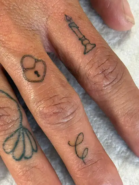 Tiny charms on the fingers: a lock, a candle, and a leaf.