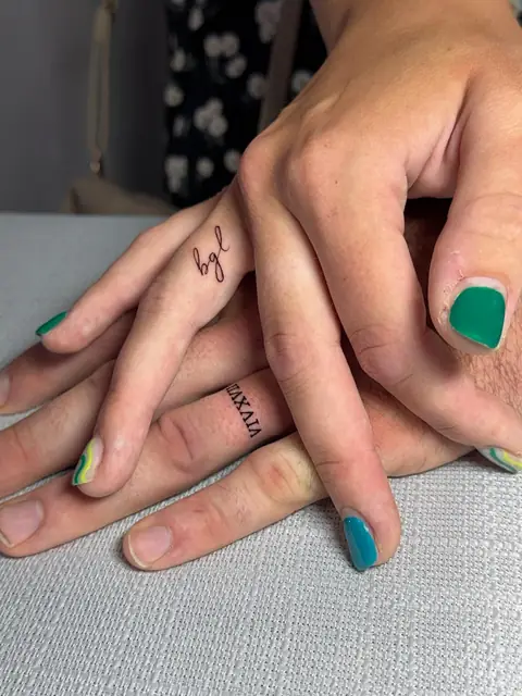 Tiny lettering on the fingers — a script initial and a Roman numeral.