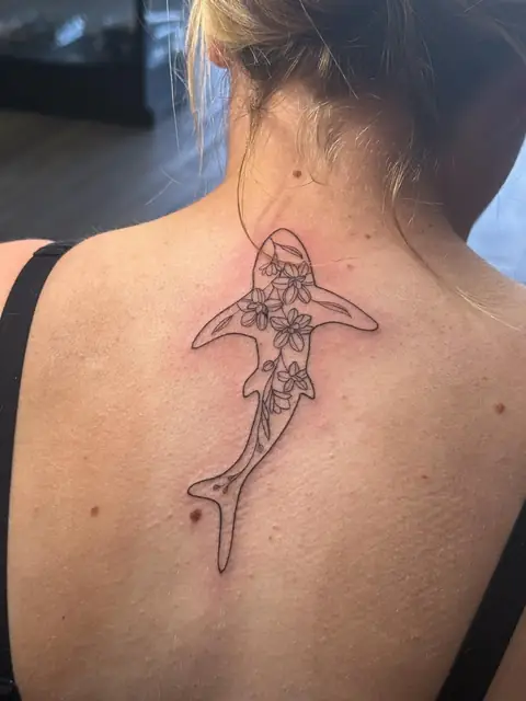 An outline of a shark, filled with flowers, on the back.