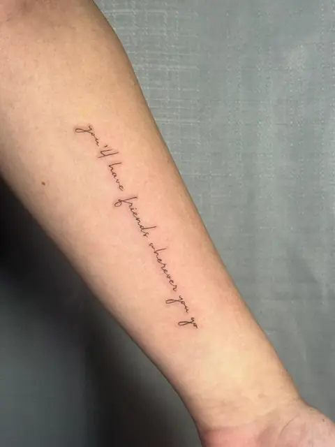 Script running down the forearm: “you'll have friends wherever you go.”