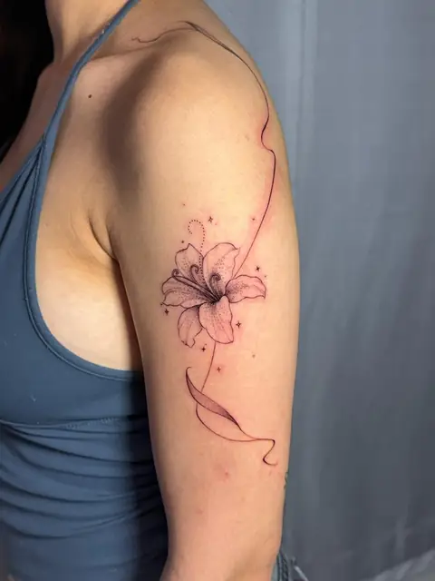 A lily on the shoulder, with a ribbon and stars around it.