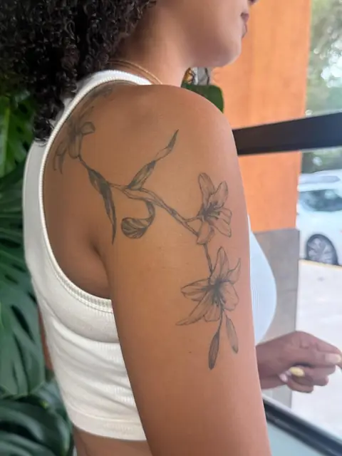Lilies running over the shoulder, healed, in fine line.
