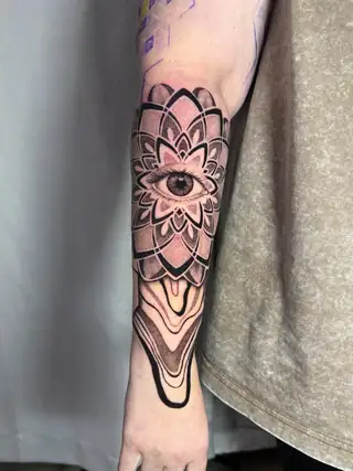 An ornamental mandala with an eye at the center, geometry running to the hand.