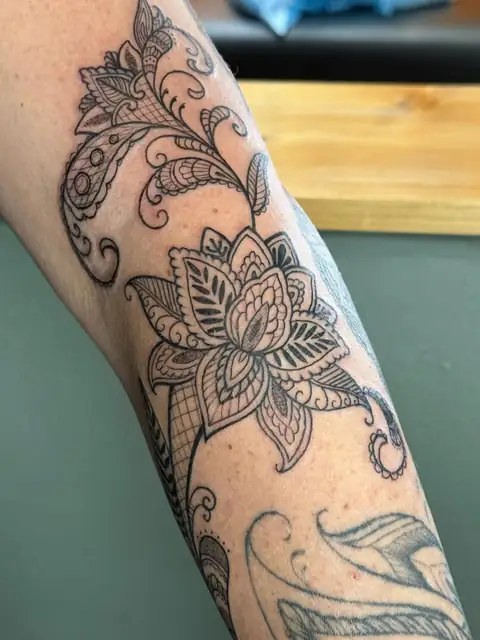 An ornamental lotus with paisley scrolls running the forearm.