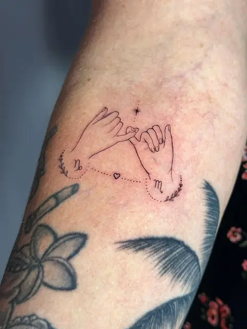 Two hands in a pinky promise, with zodiac marks and a star between them.