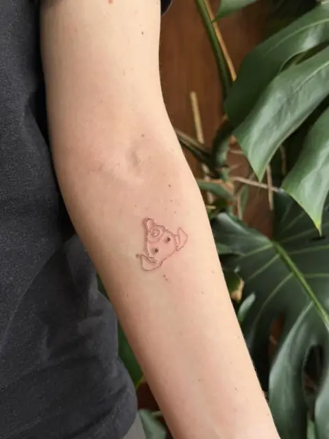 A tiny dog in fine line — just a silhouette on the arm.