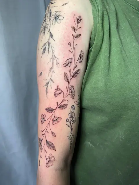 Fine-line morning glories climbing the upper arm.